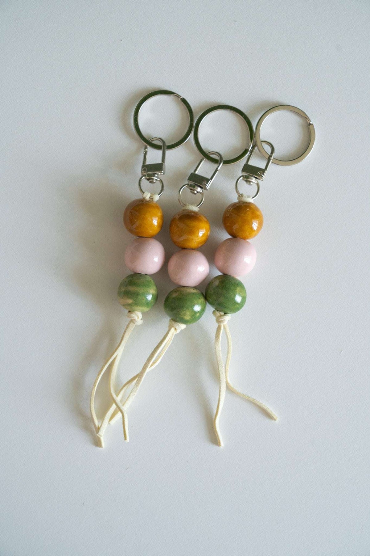 Ceramic bead keychains with metal rings, orange and pink beads, green beads, white tassel cords