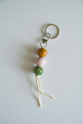 Ceramic bead keychain with metal ring, orange, pink, and green beads, white tassel cord