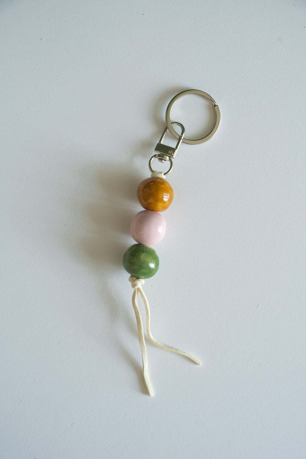 Ceramic bead keychain with metal ring, orange, pink, and green beads, white tassel cord