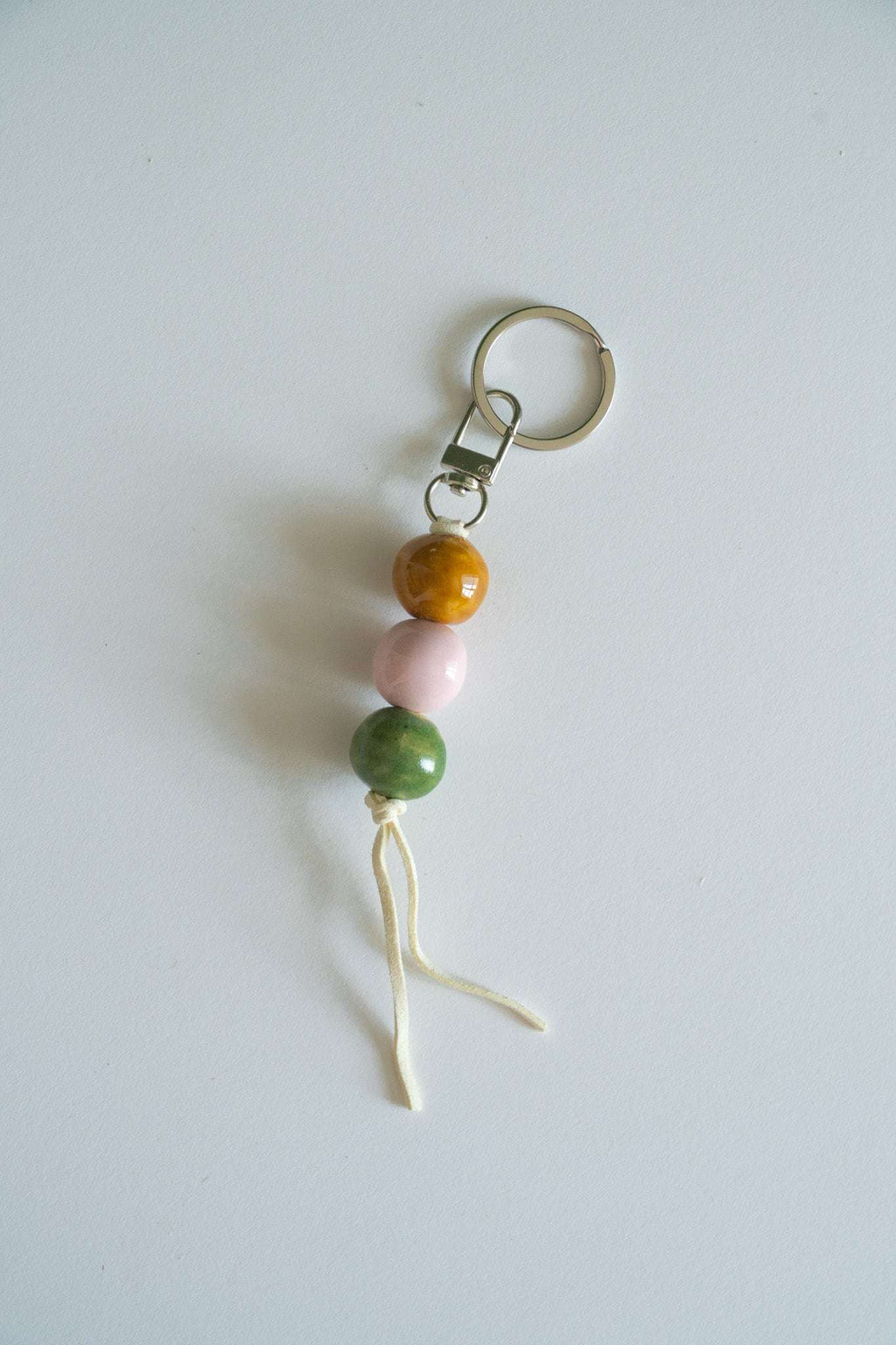 Ceramic bead keychain with metal ring, orange and pink beads, green bead, white tassel cord