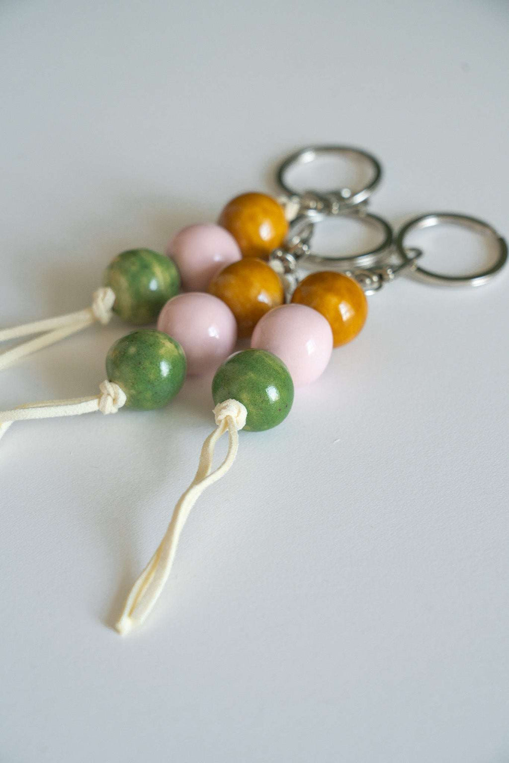 Ceramic bead keychains close-up with metal rings, orange, pink, and green beads, white cords
