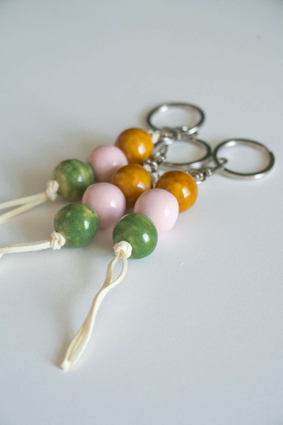 Ceramic bead keychains with metal rings, orange, pink, and green beads, white tied tassels