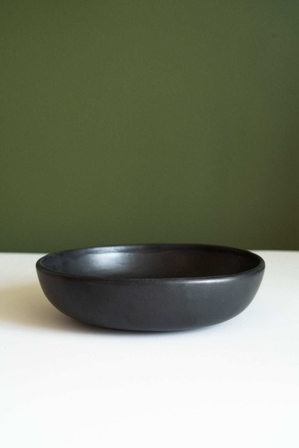 Black matte stoneware pasta bowl, empty, centered on a white surface