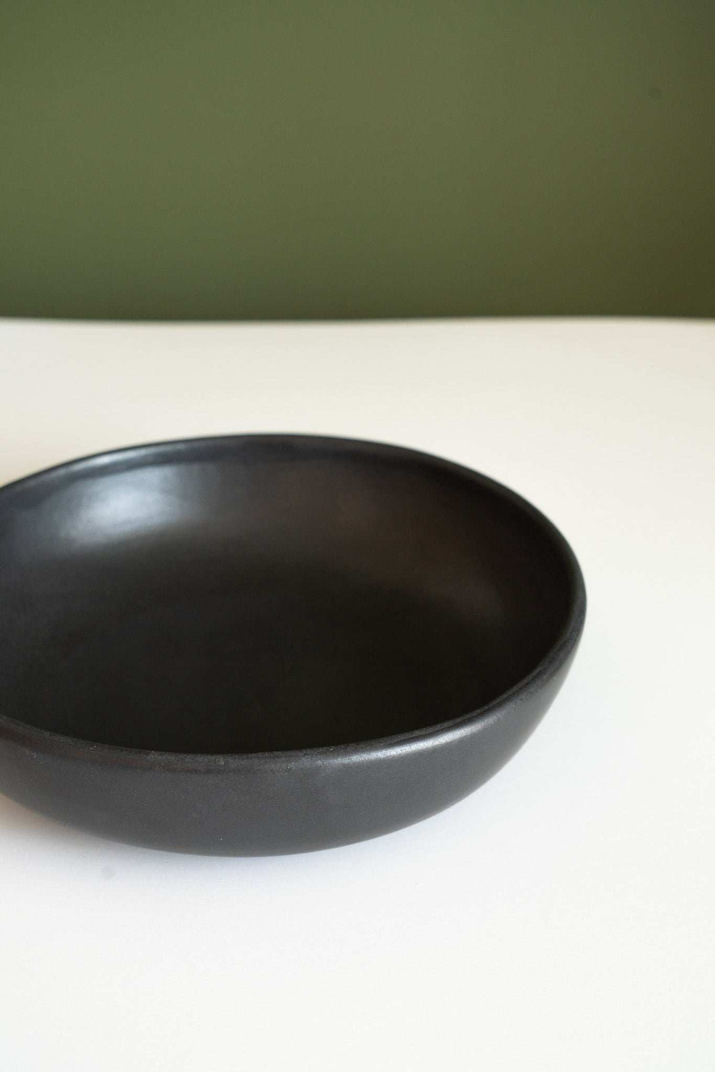 Black matte stoneware pasta bowl, close-up of rim and interior, empty