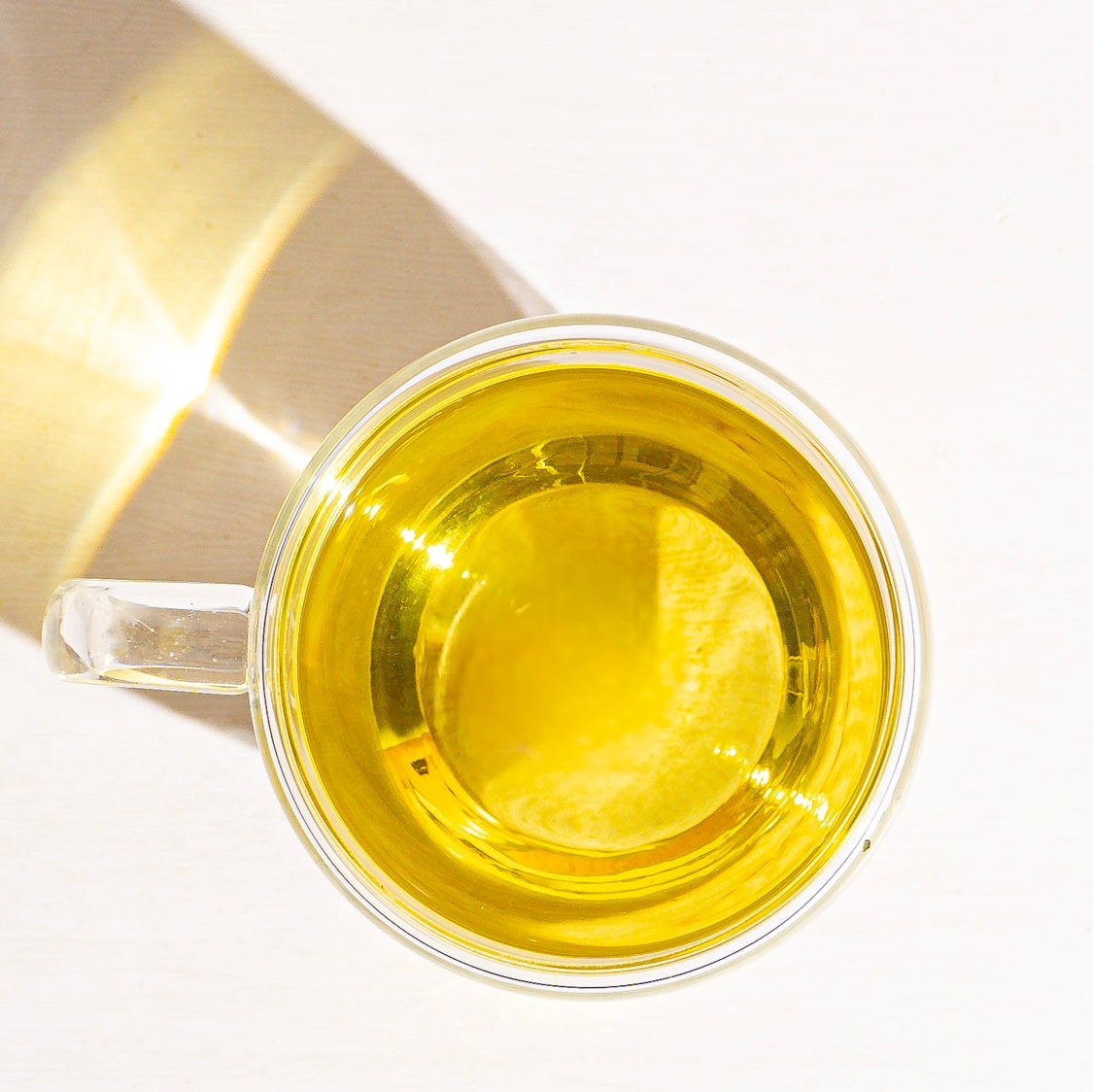 Clear glass cup of golden chamomile tea with steeped herbs