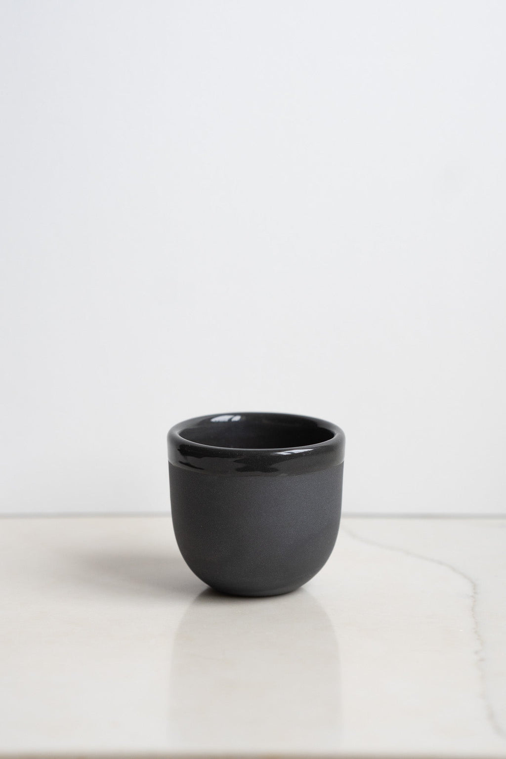 Handmade porcelain espresso cup in dark charcoal, rounded short body, no saucer