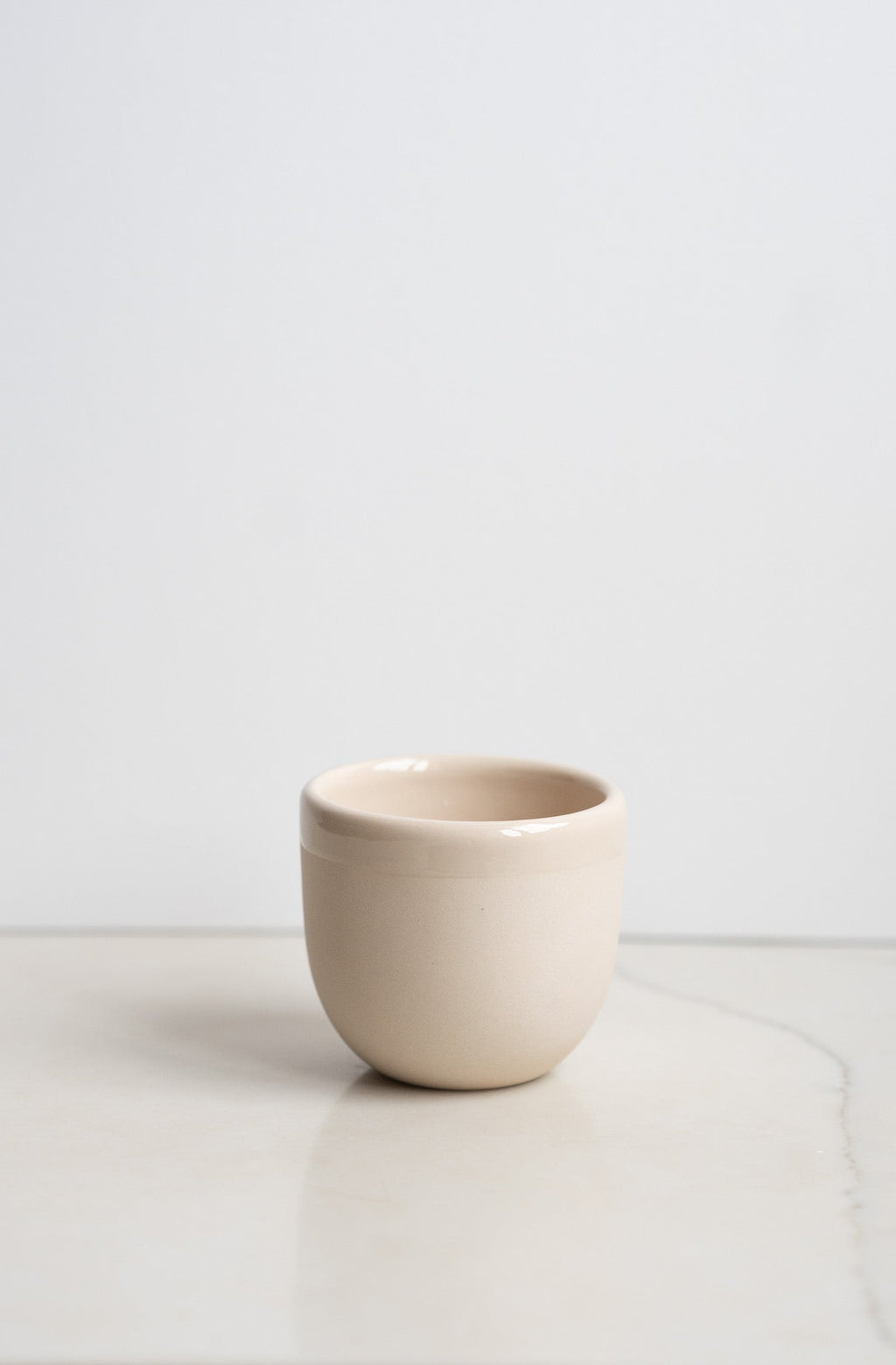 Handmade porcelain espresso cup in light beige, rounded short body, no saucer