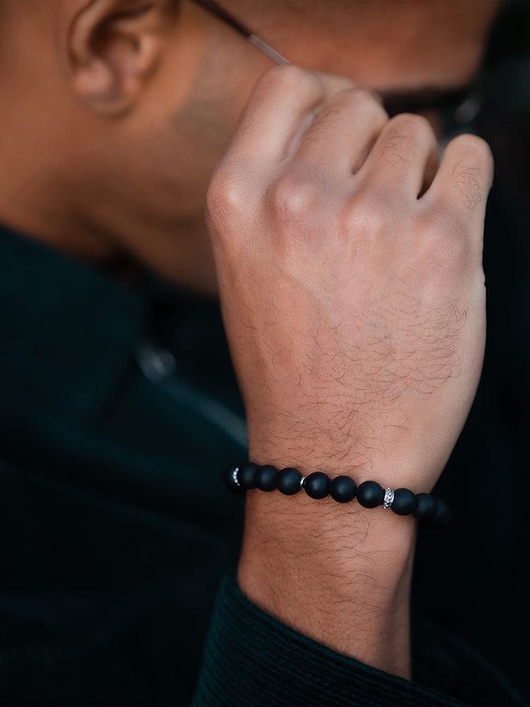 Black beaded bracelet on wrist with small round beads and adjustable cord tie