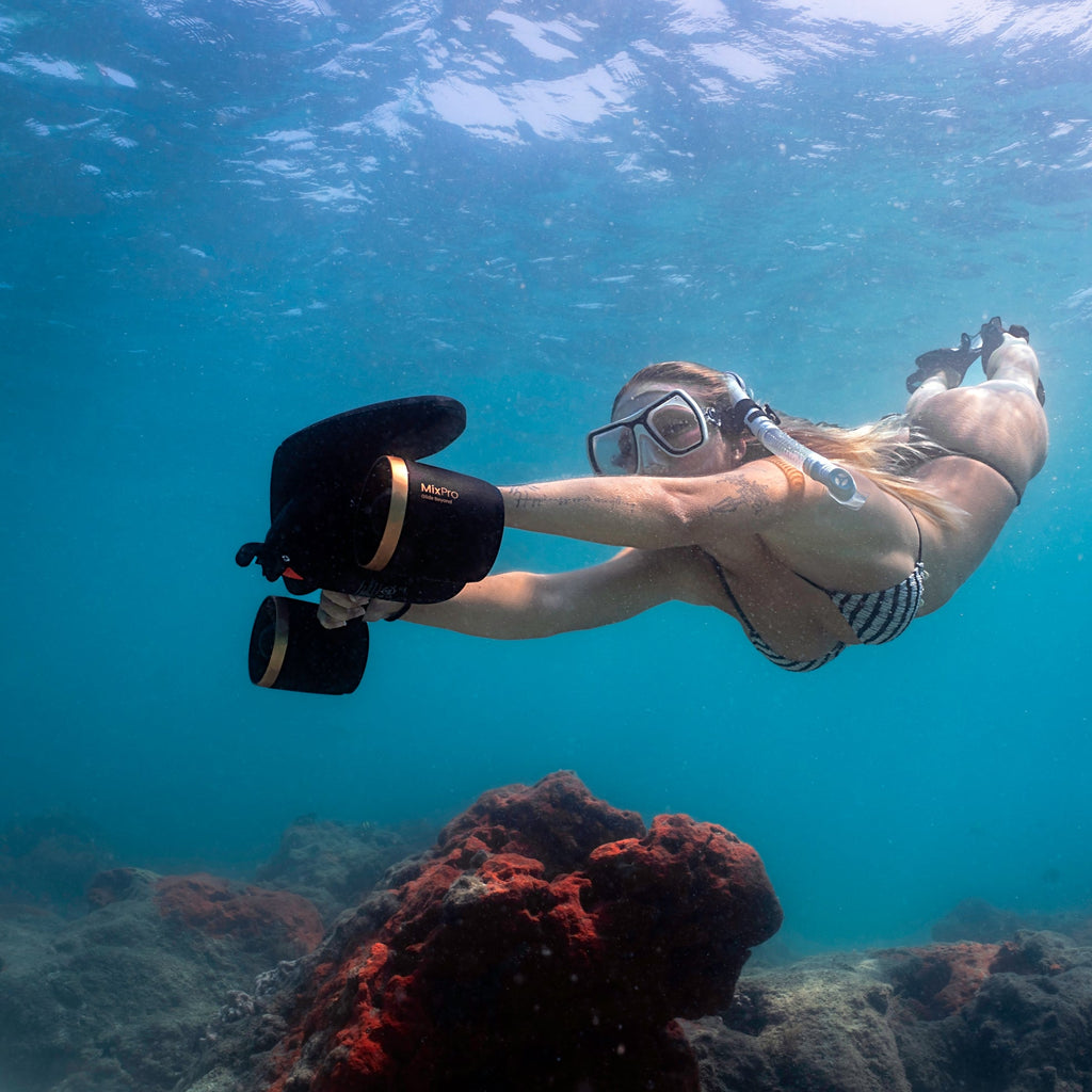 Black underwater camera mounted on handle, diver swimming underwater