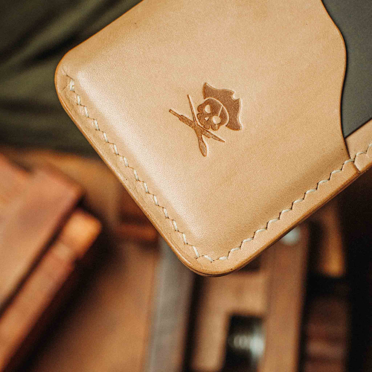 Tan leather minimalist wallet corner with embossed emblem and contrast stitching
