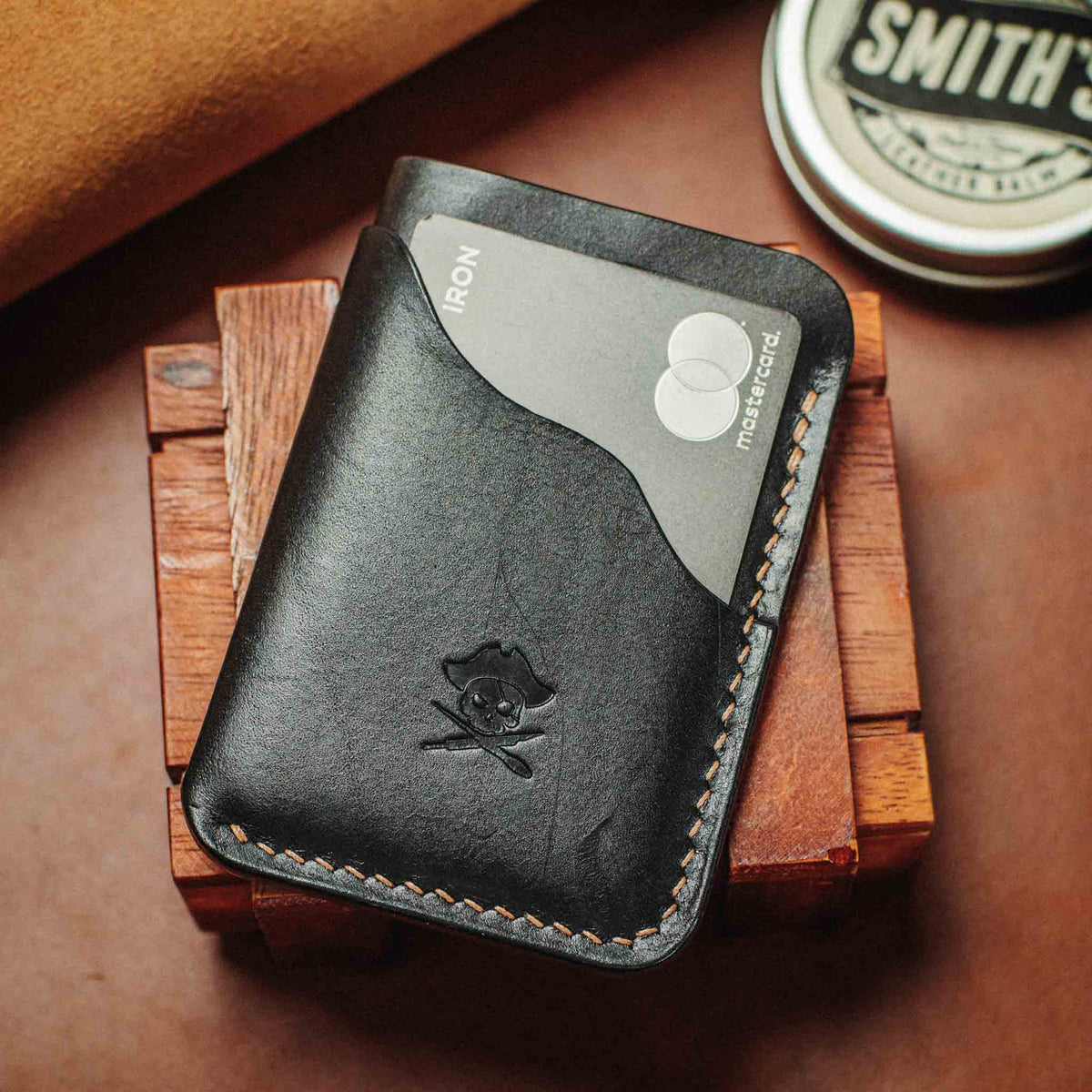 Black leather wallet with embossed skull emblem and yellow edge stitching