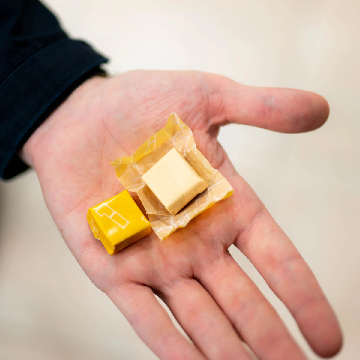 Energy chew pieces and small yellow wrappers in open palm