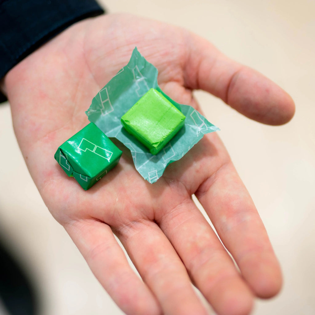 Green energy chew cubes in hand with small foil wrappers