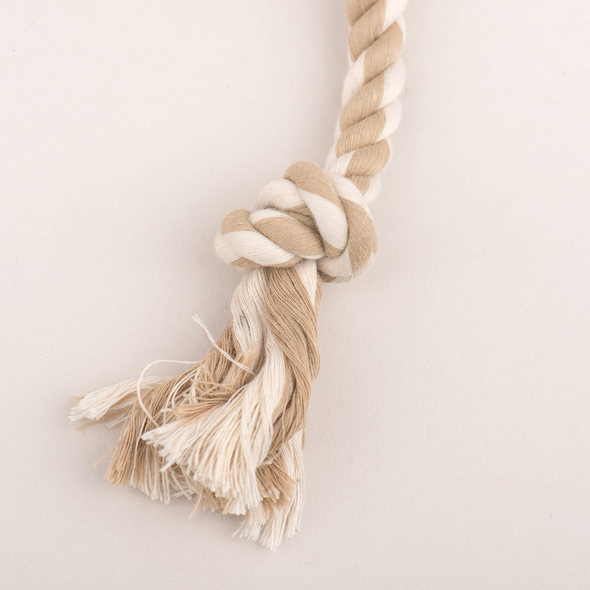 Beige rope tug dog toy with knotted end and fringe tassels