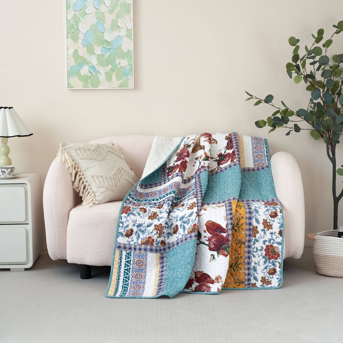 Quilted patchwork throw blanket draped over sofa; blue and floral panels with red and yellow accents