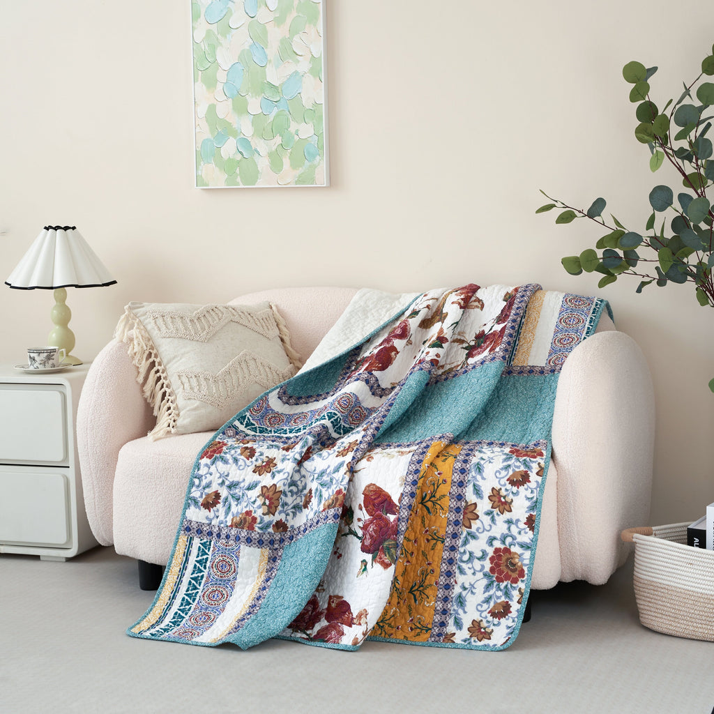 Quilted patchwork throw blanket featuring blue, white, and patterned panels with floral bird motifs
