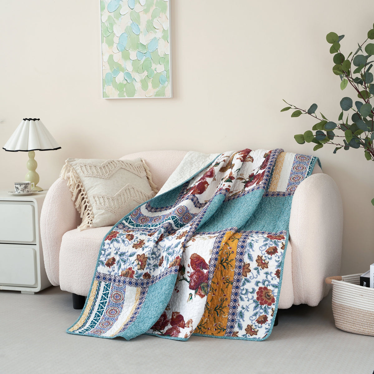 Quilted patchwork throw blanket featuring blue, white, and patterned panels with floral bird motifs