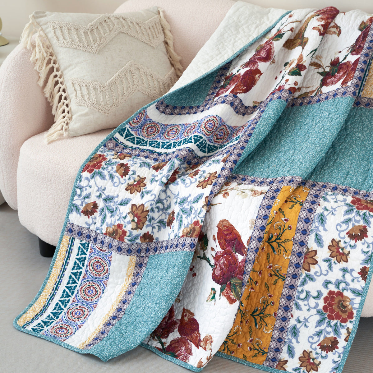 Close-up of quilted patchwork throw blanket with blue speckle, floral print, and gold strip panel