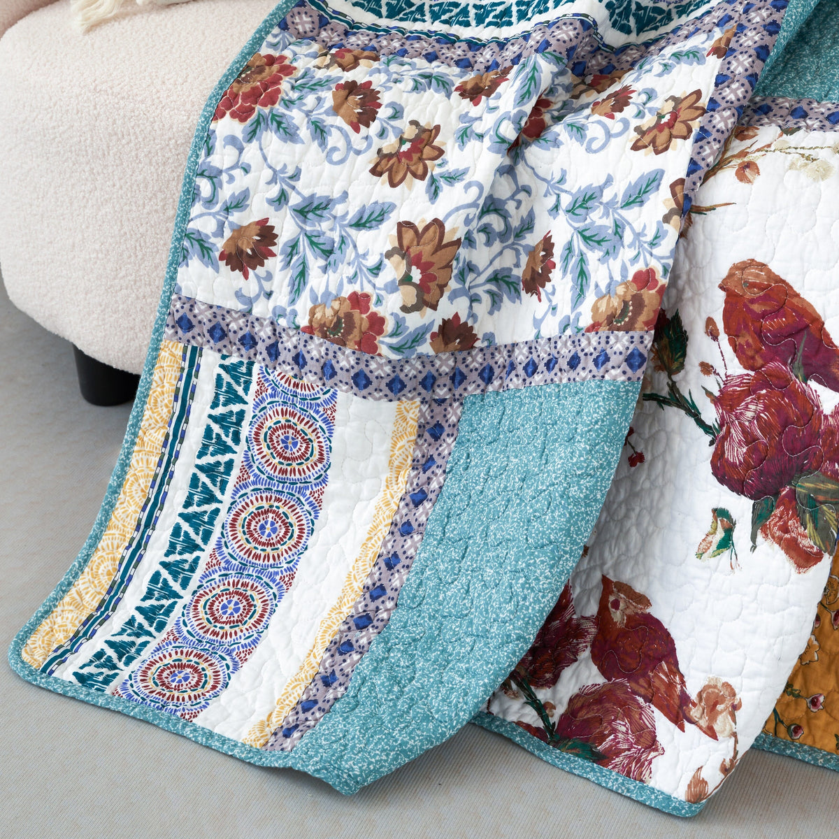 Quilted patchwork throw blanket close-up; blue fabric border with floral and bird print squares