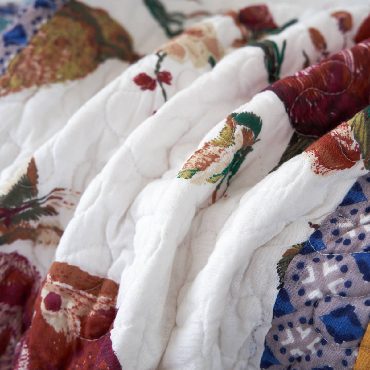 Quilted patchwork throw blanket with hummingbird motifs, pastel blue, red, and yellow blocks