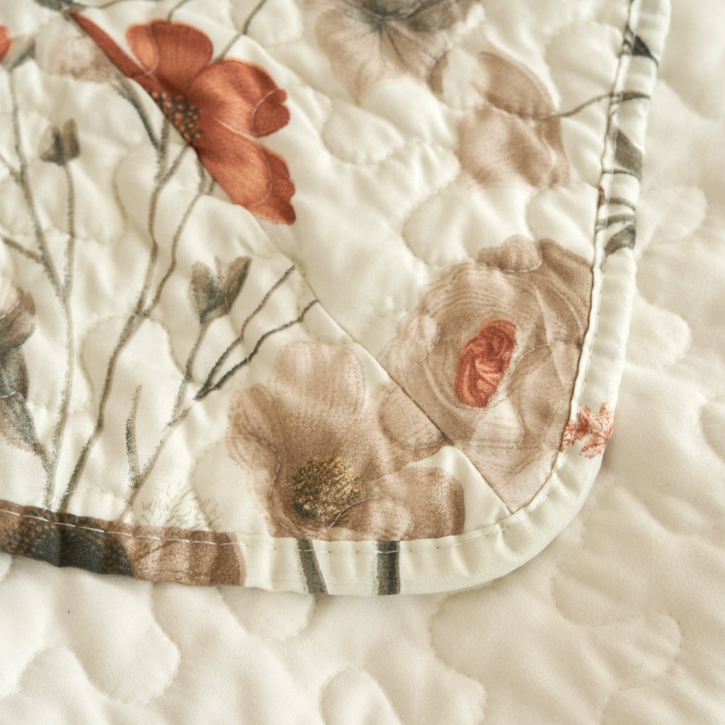 Floral quilt corner with off-white fabric, beige, rose, and green botanical print trim.