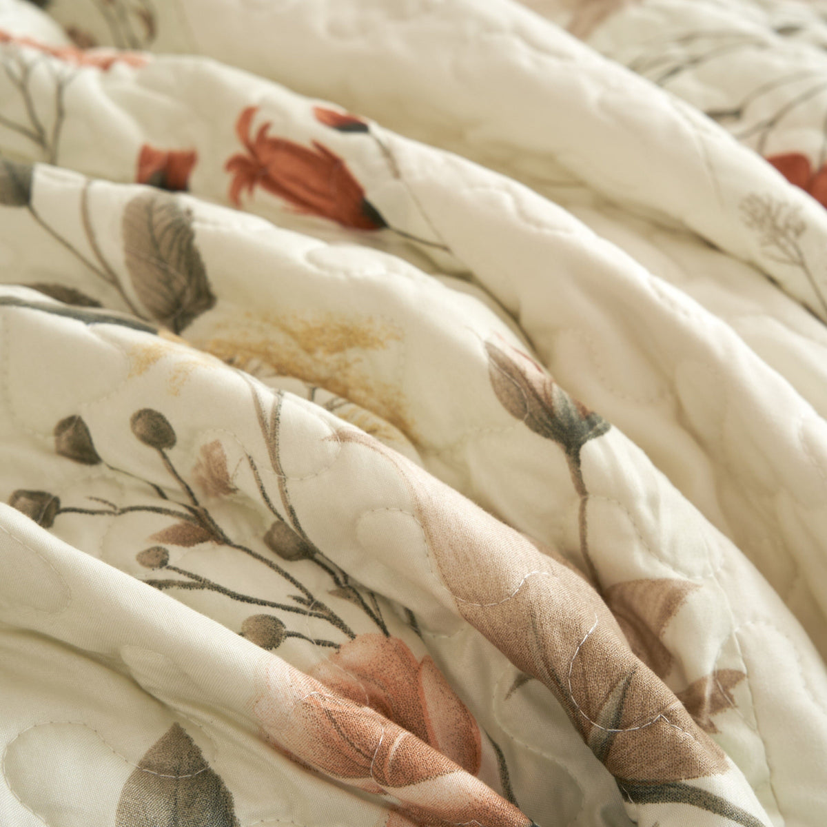 Off-white floral quilt with stitched channels and botanical vine print in beige and rose tones.