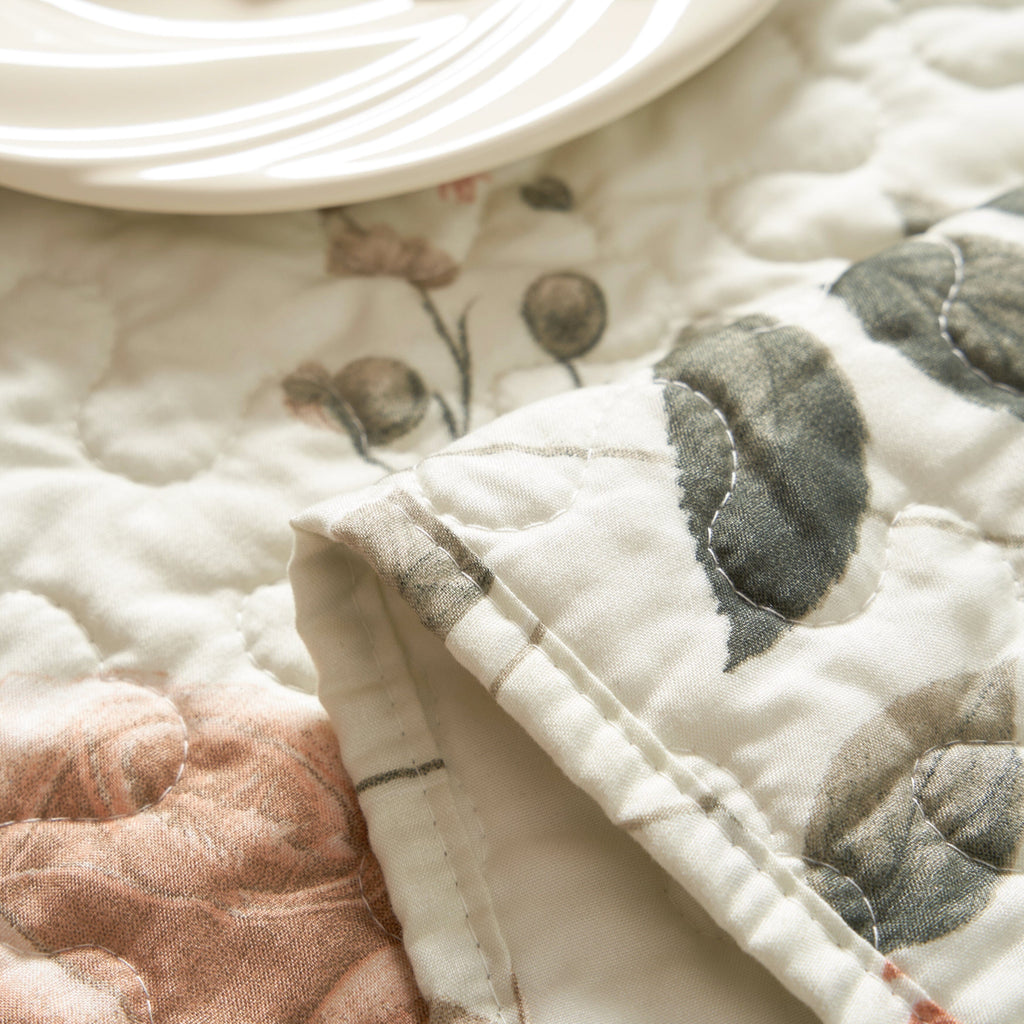 Quilted microfiber table runner fabric close-up, beige with rose and olive floral motifs