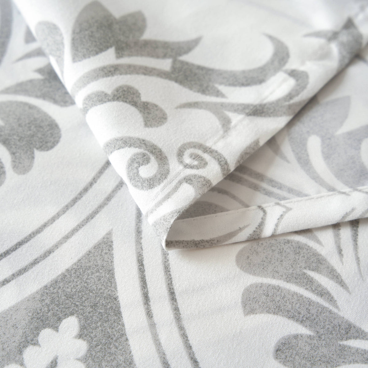 Fabric close-up of gray and white damask sheets with soft drape