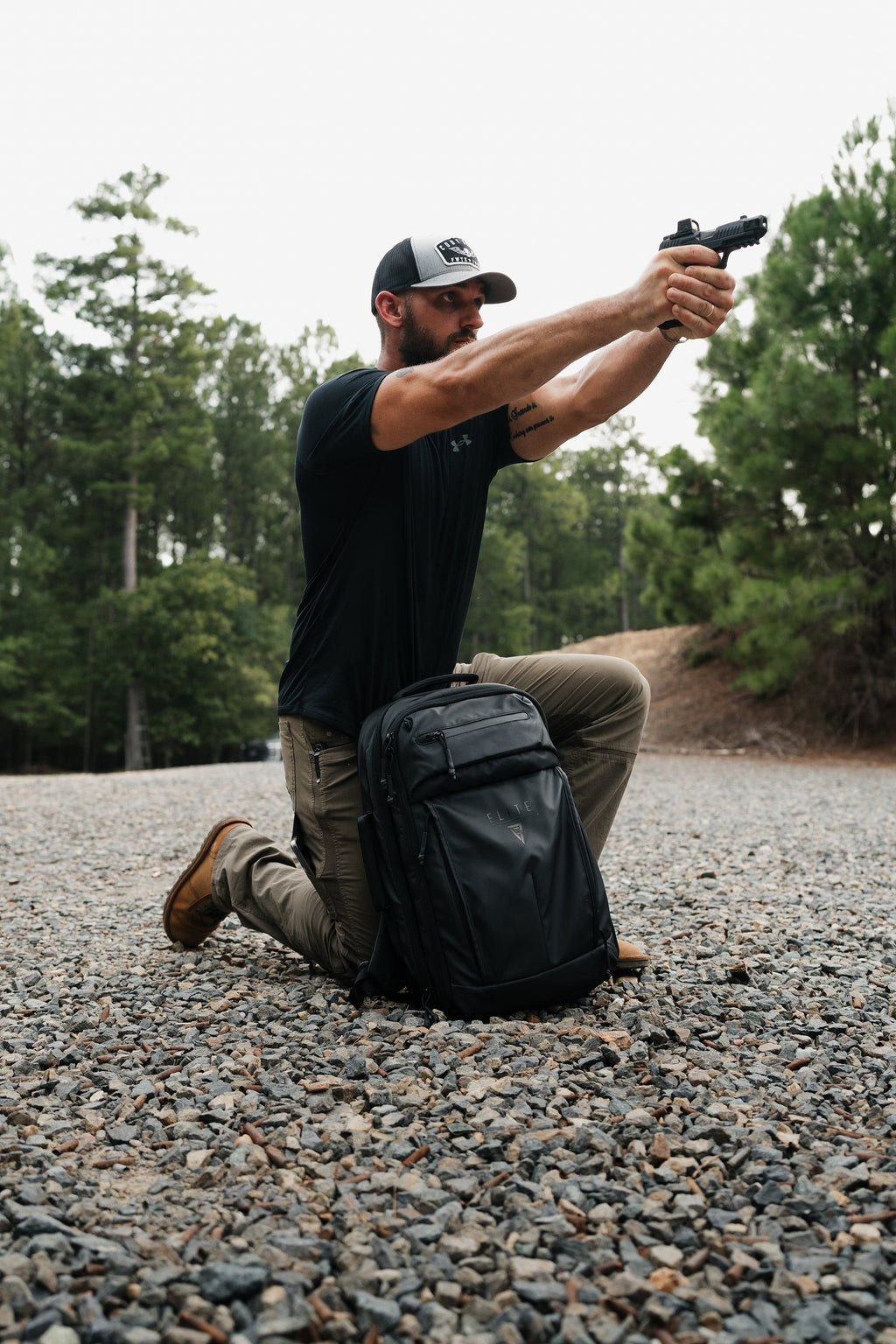 Dark backpack lying on gravel with side pockets and zipper pulls visible
