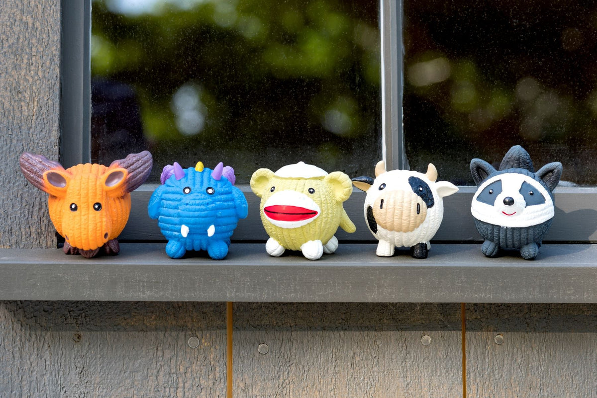 Assorted small latex dog ball toys in different colors lined up on a ledge