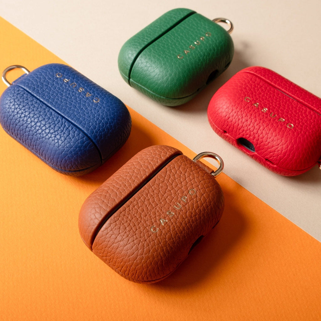 Red leather AirPod case on a color block with blue, green, and brown cases