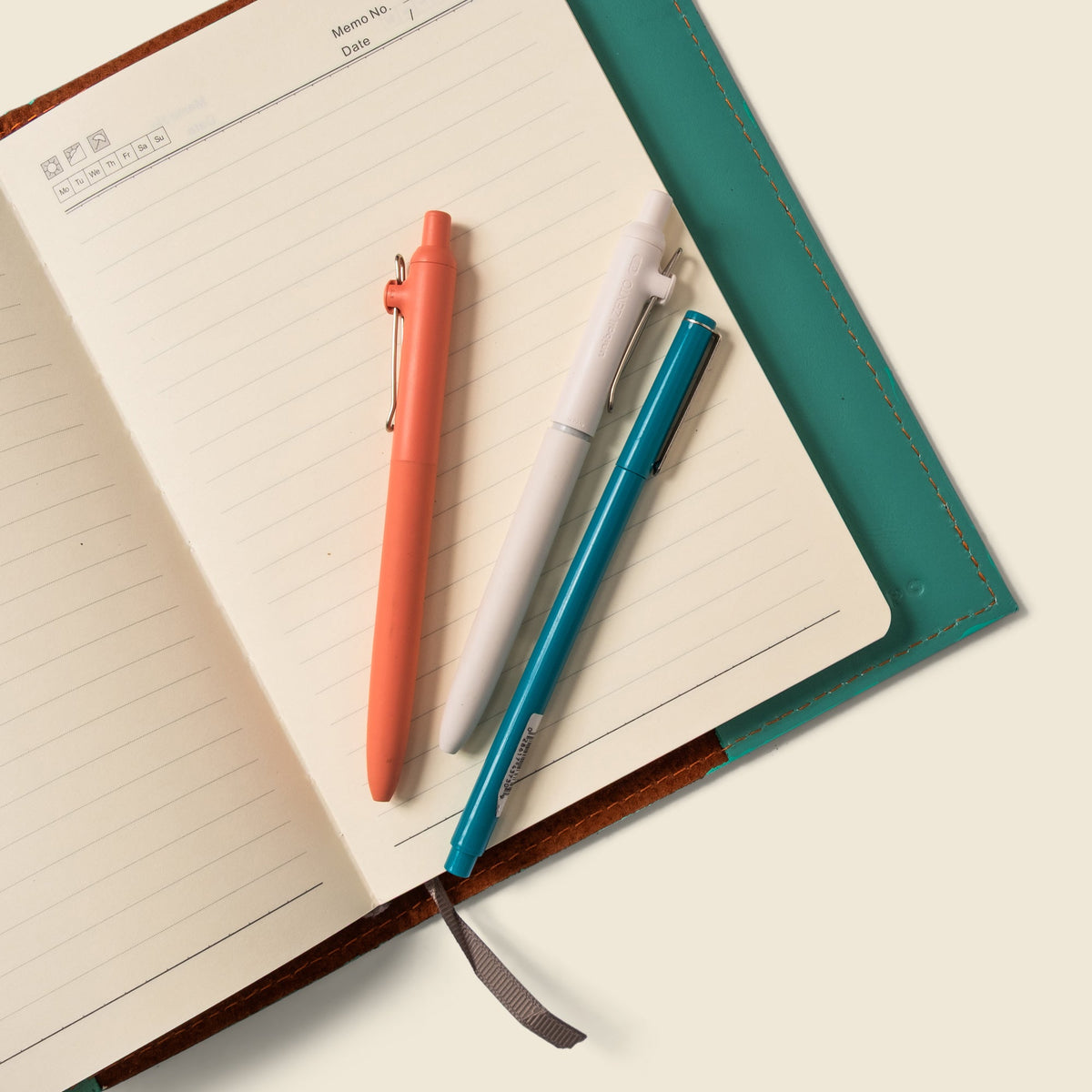 Teal leather notebook cover corner with visible brown backboard and gray strap pull.