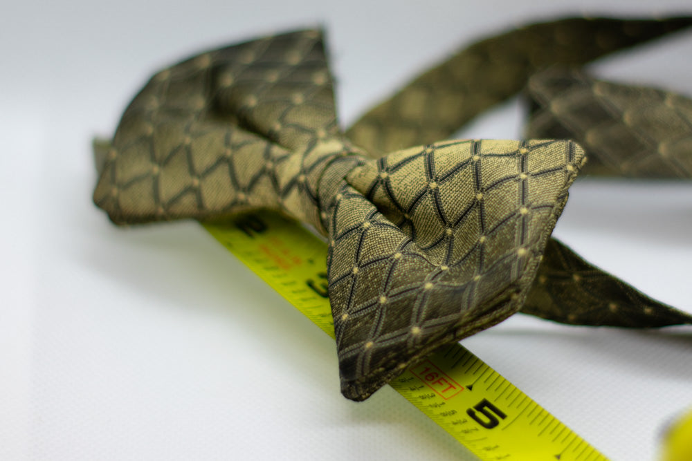 Adjustable bow tie in dark olive green with gold geometric weave; length marked