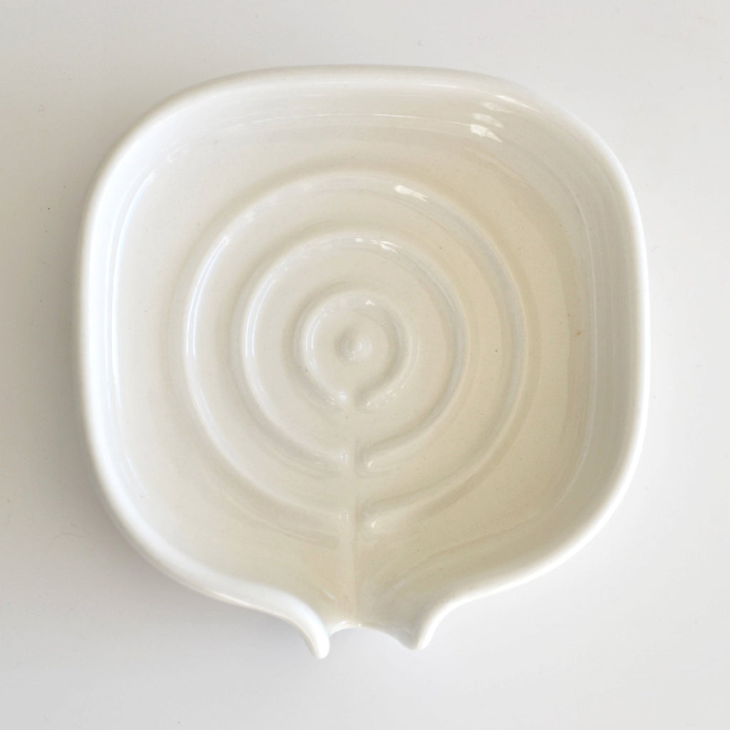 White glossy porcelain soap dish with swirl drain pattern in the base