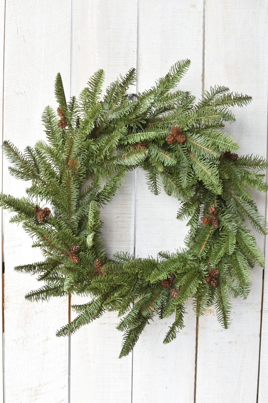 Green faux spruce wreath with clustered faux pinecones