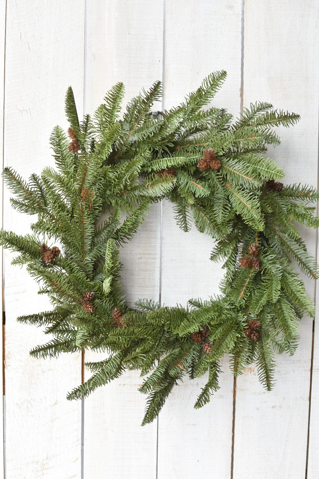 Green faux spruce wreath with clustered faux pinecones