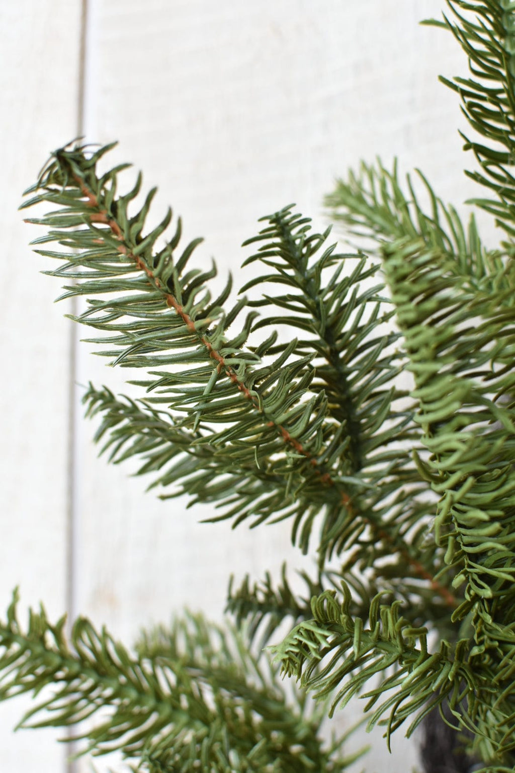 Faux spruce wreath with dense needle branches and brown stem lines