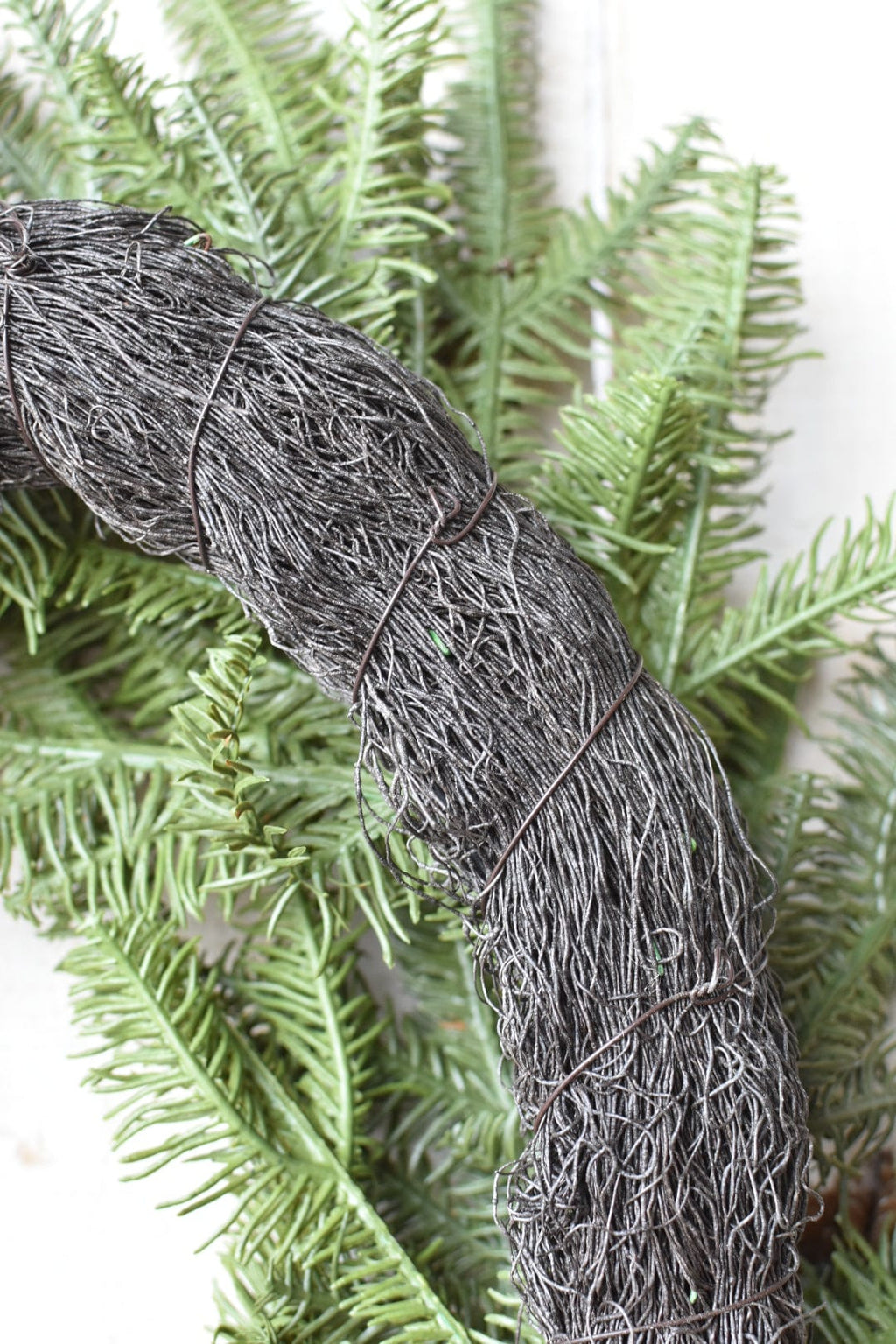 Gray rope tie wrapped around the faux spruce wreath