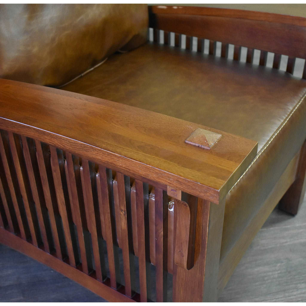 Wood armrest and brown leather-look seat cushion detail on arm chair