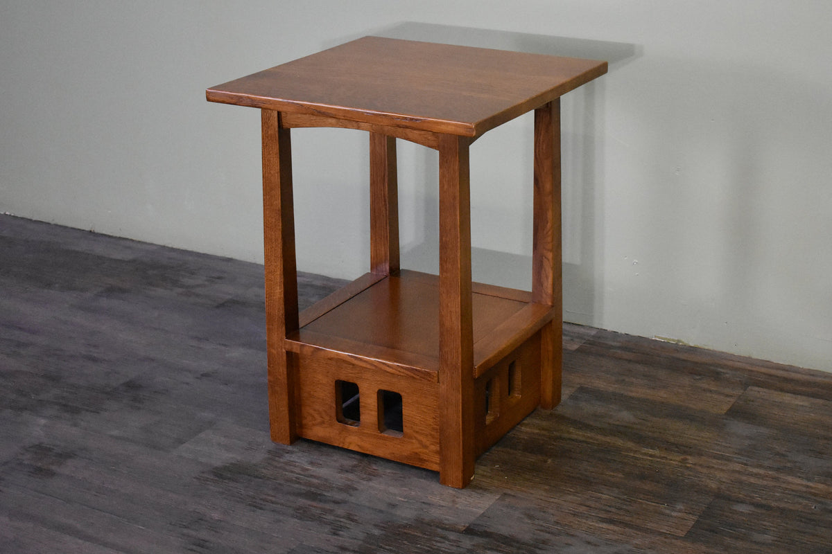 Mission-style wood taboret end table with open lower shelf and two cutout panels.