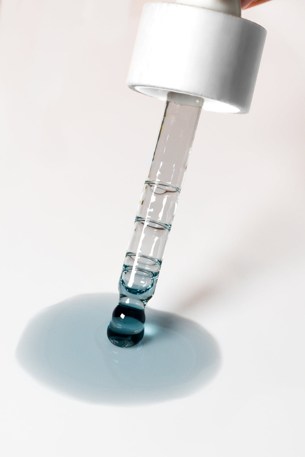 Dropper dispensing clear gel into a blue serum puddle
