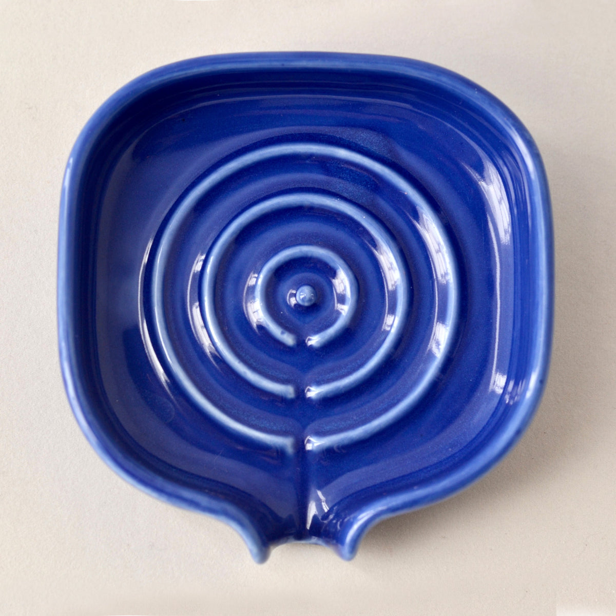 Top view of cobalt blue porcelain self-draining soapdish with circular drain detail