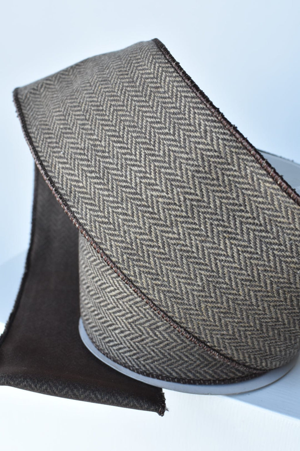 Brown and tan woven herringbone ribbon with dark edge and red-brown stitch detail