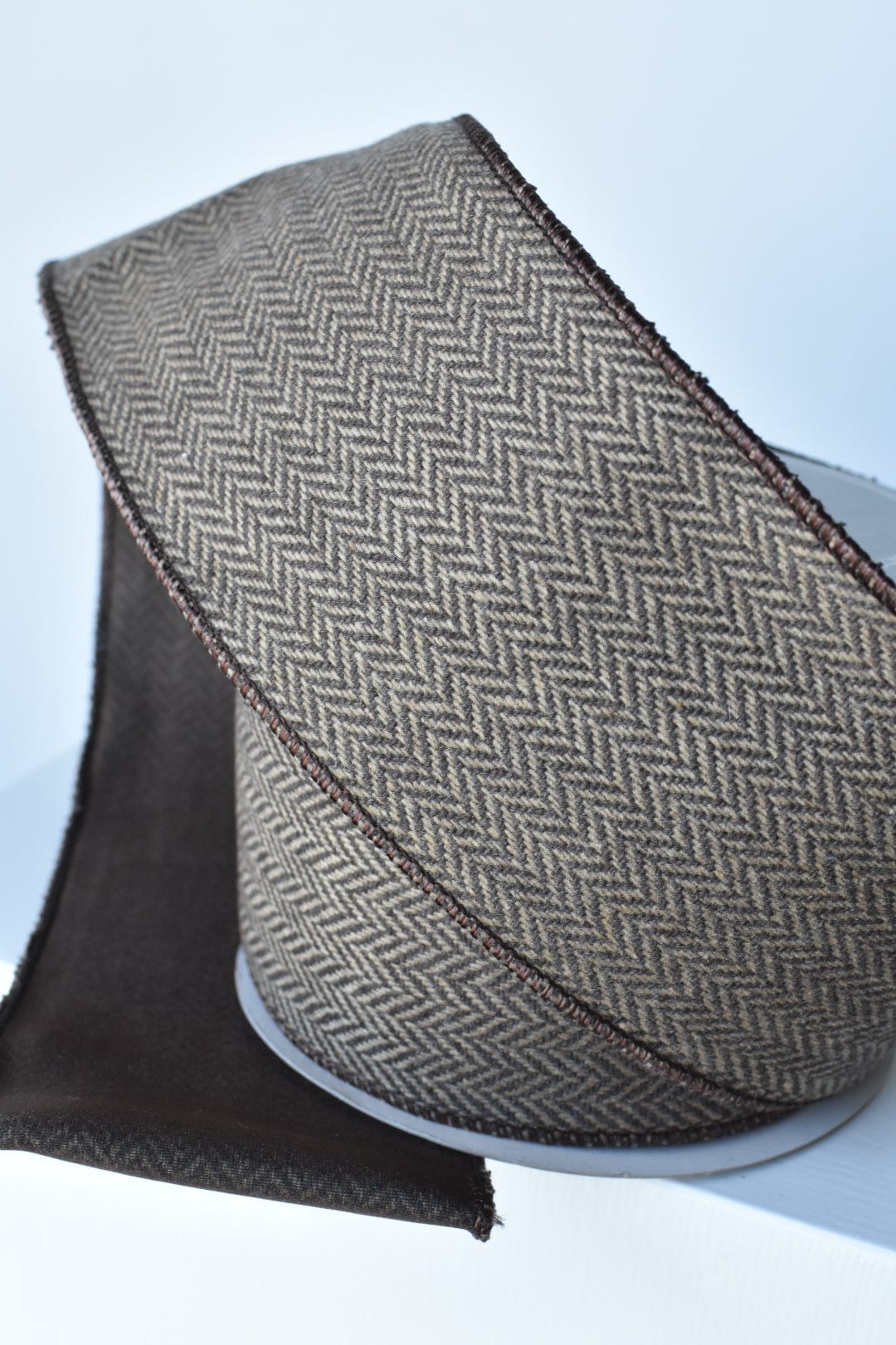 Brown and tan woven herringbone ribbon with dark edge and red-brown stitch detail