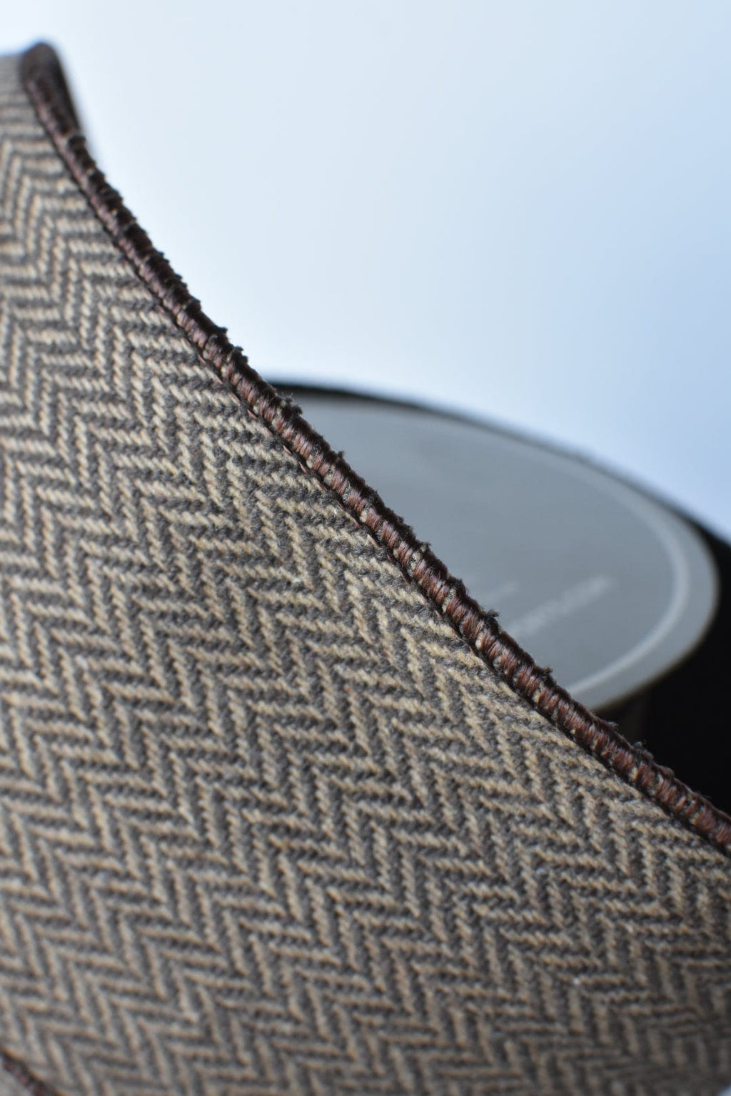 Brown and tan herringbone ribbon with dark woven border along the rolled edge