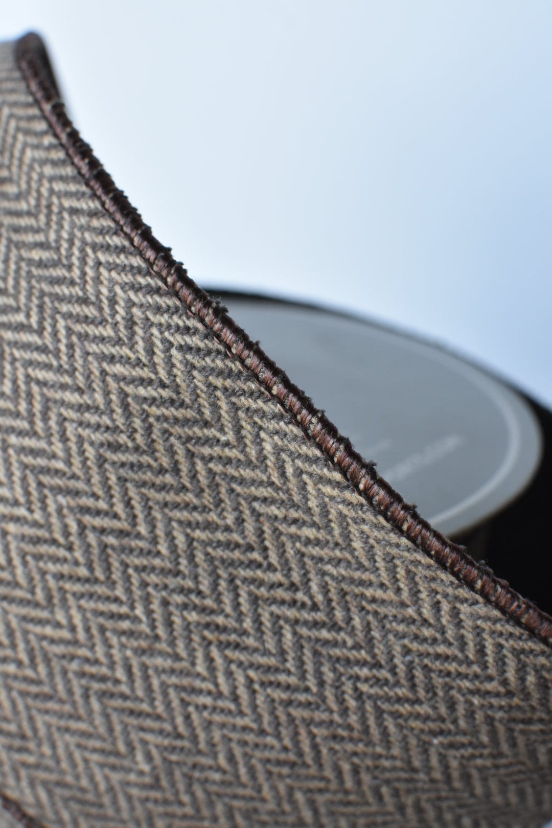 Brown and tan herringbone ribbon with dark woven border along the rolled edge