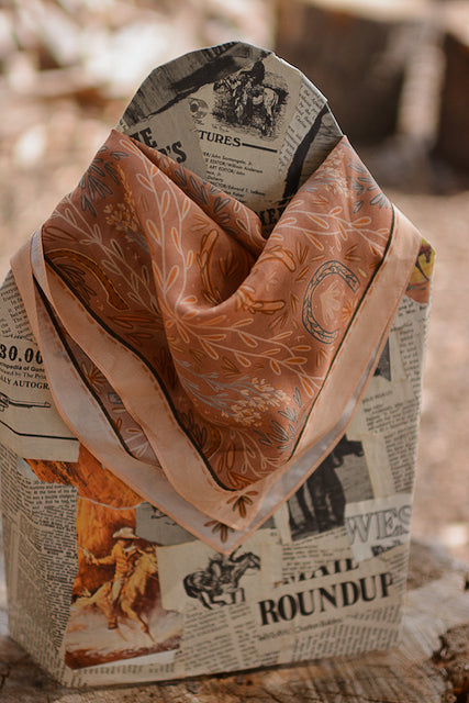 Dusty rose wild rag scarf with tag label on folded fabric, paisley and floral print