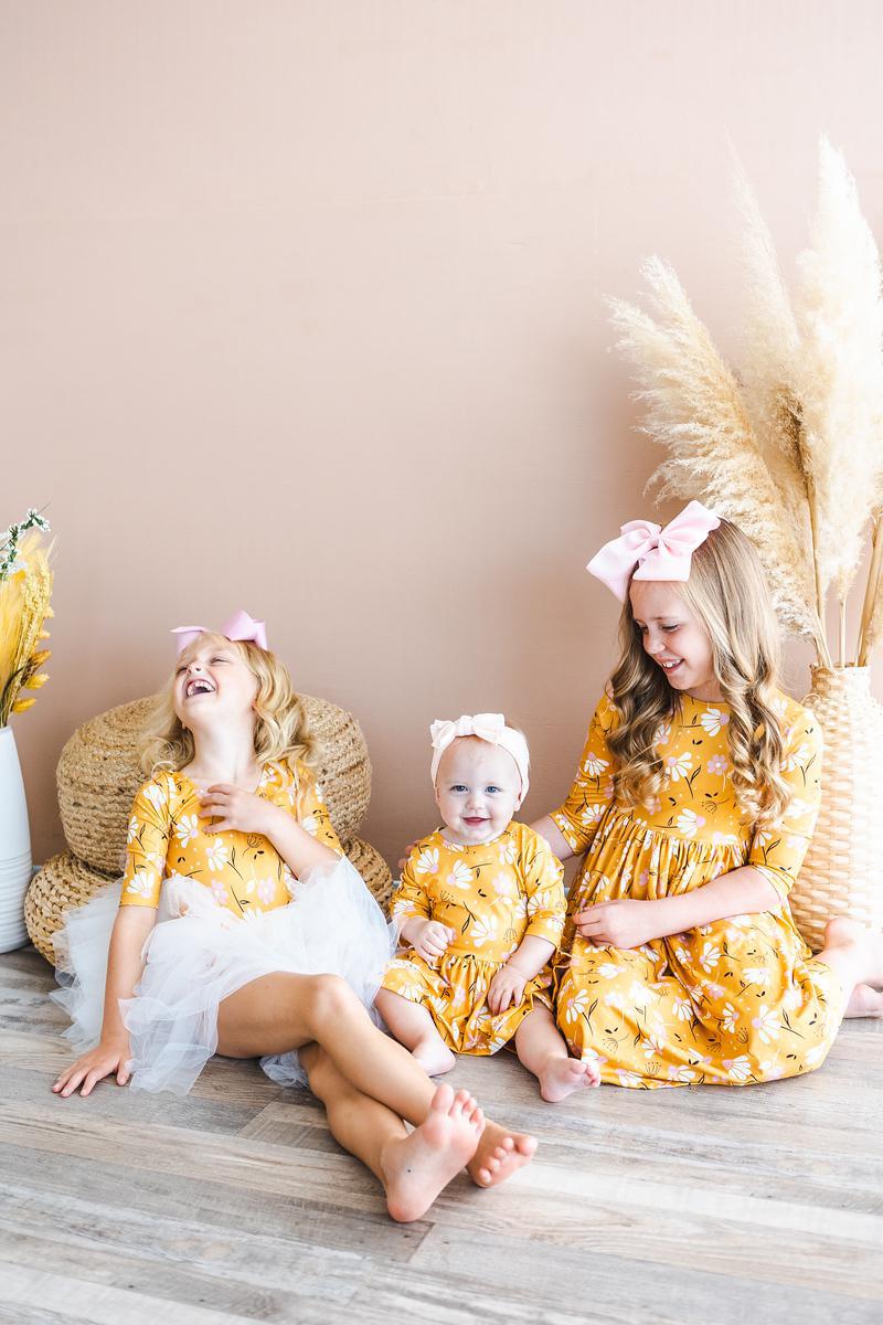 Girls orange floral twirl dress in family photo, showing 3/4 sleeves and gathered waist