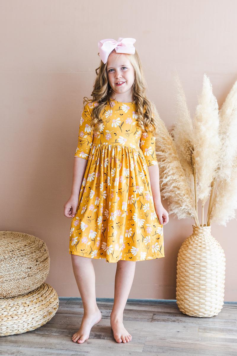 Girls orange floral twirl dress standing full-length with gathered waist and 3/4 sleeves