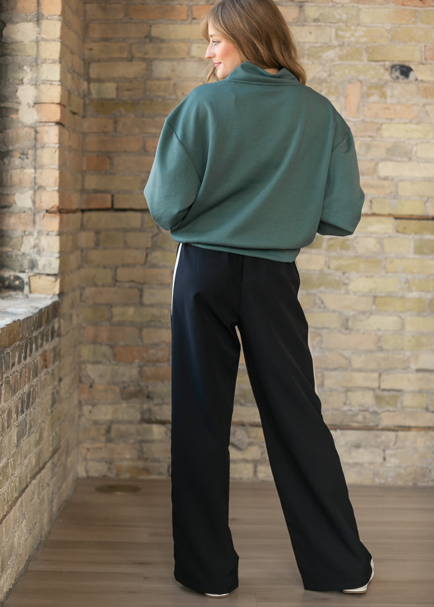 Nina wide-leg track pants, dark with white side stripe detail at the back.